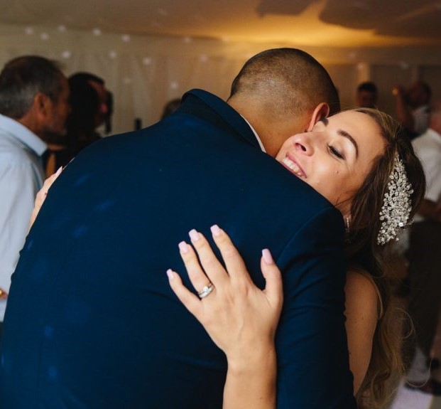 A young newly wed couple share an embrace at their wedding. 